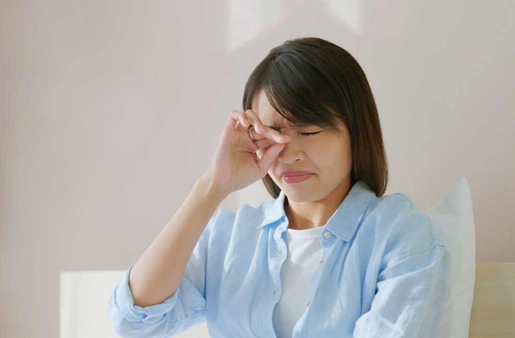 A person closes their eyes and rubs one eye with their hand while appearing to be in discomfort.
