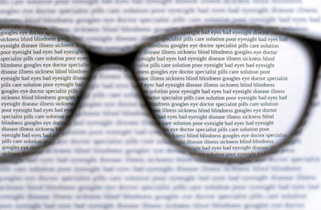 Unfocused words around black eyeglasses with a view of sharp text through the lenses.