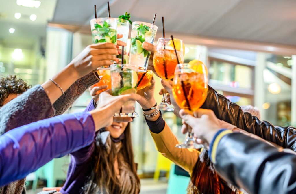 People holding drinks, clinking the glasses to cheers each other.