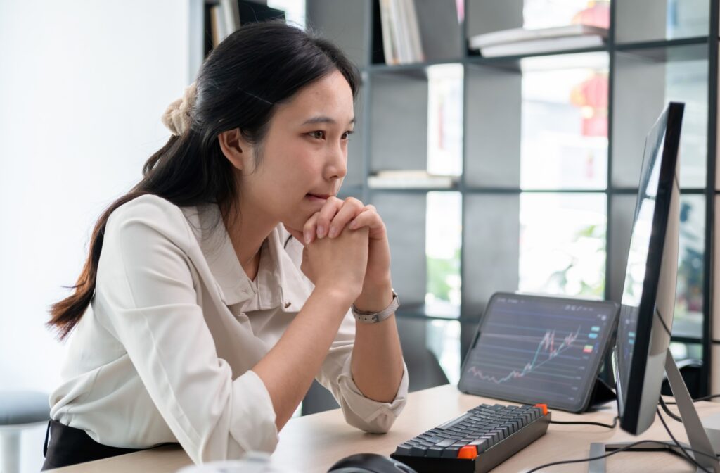 A person in an office, starring at a computer screen up close, which can contribute to the progression of myopia.