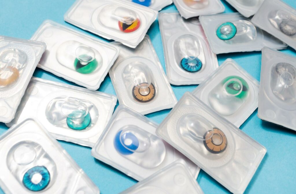 A bunch of colored contact lenses in blister packs on a blue surface.