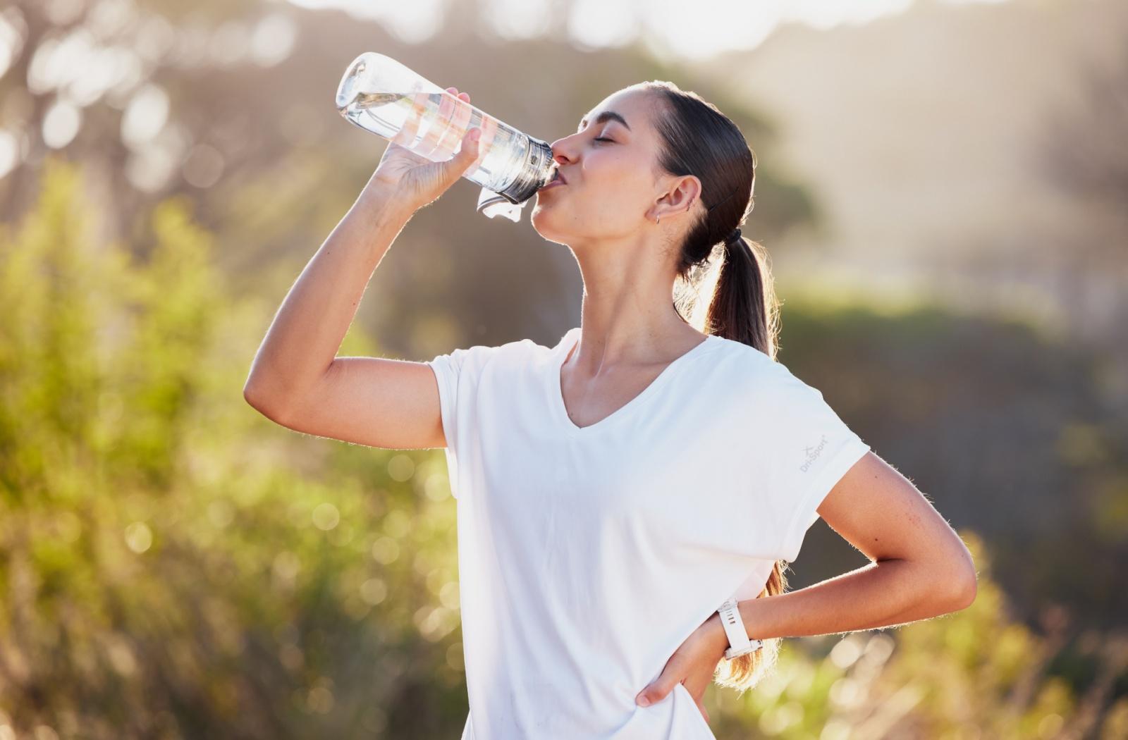 A person drinking water to stay hydrated and avoid puffy eyes.
